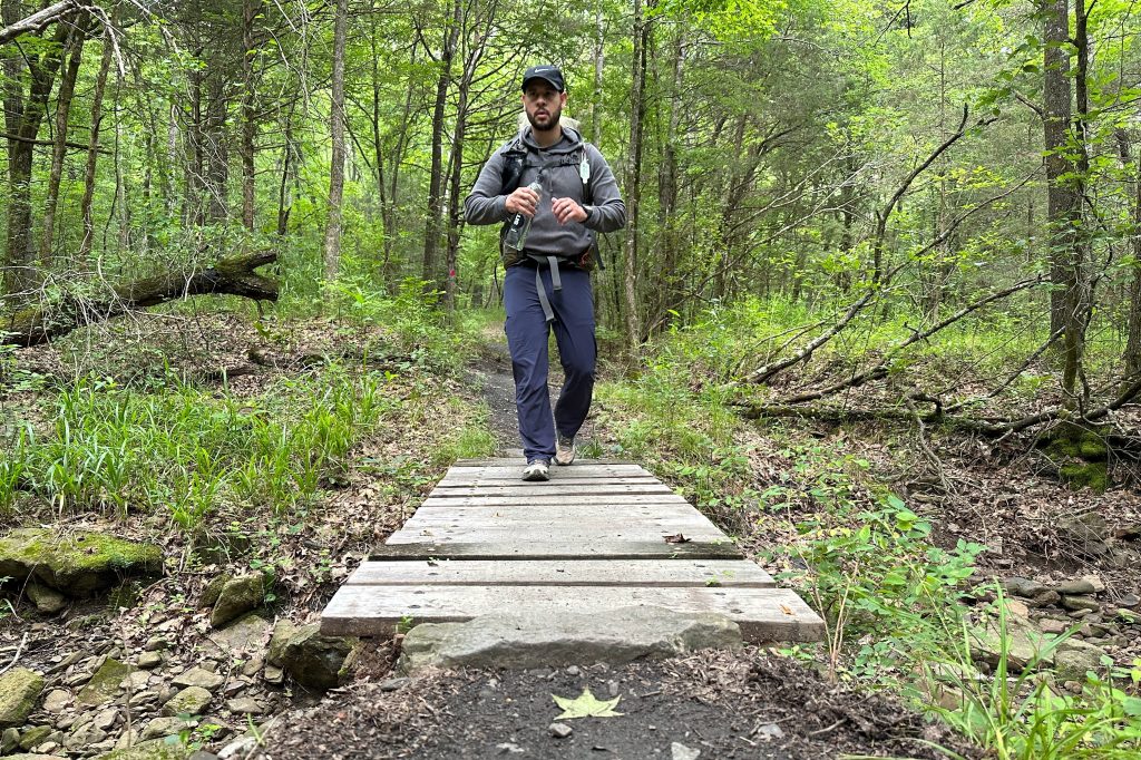 A man walking on a nature trail with backpacking gear
