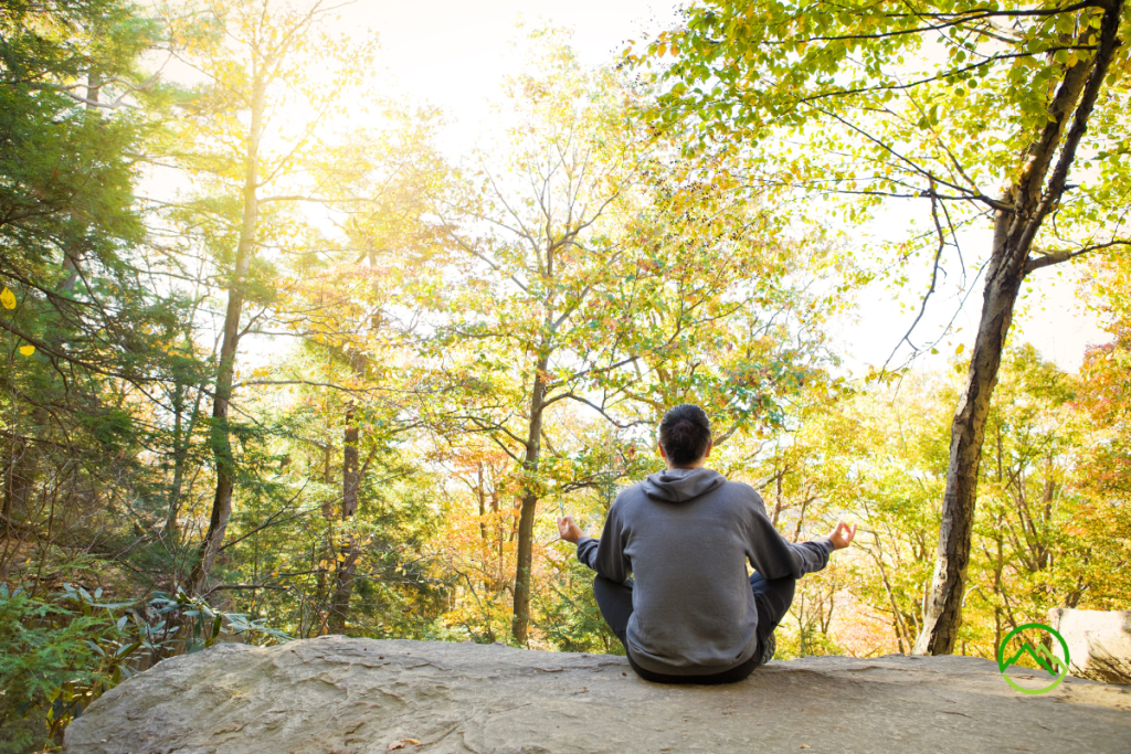 A man sitting down meditating in nature